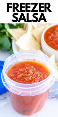 two plastic containers filled with salsa next to tortilla chips and cilantro