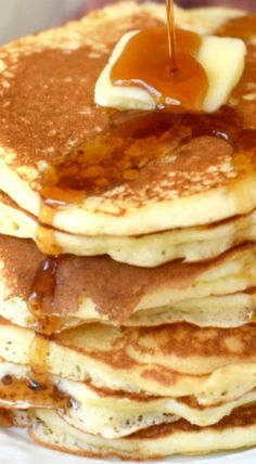 a stack of pancakes with syrup being poured on top