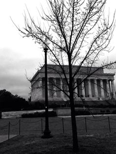 a black and white photo of the lincoln memorial in washington d c, with bare trees