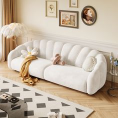 a white couch sitting on top of a hard wood floor next to a wall with pictures