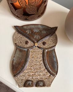 an owl shaped candle holder sitting on top of a white table next to a vase