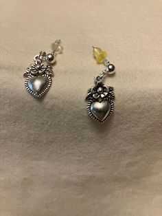 These dainty silver tone earrings consist of a 4mm ball post insertion stud with a little, one-sided 3D charm dangle. The charm shows a simple flower with a small heart below it. The earrings measure approximately 1 inch in length and come with butterfly backs. You can choose to add a drawstring gift bag for $1 in the dropdown.  Disclaimer: all measurements are approximate, as I only have a tactile tape measure that measures in half inches. Shades may vary based on lighting and your monitor. Colors were chosen with the assistance of friends and family or based on the description of the materials I bought. If you have an idea or request for a custom design, I will do my best to find materials and create your perfect item. I try to be accurate when listing my materials but I make no promises Trendy Sterling Silver Dangle Jewelry, Hypoallergenic Drop Earrings For Valentine's Day, Sterling Silver Dangle Flower Earrings For Gifts, Hypoallergenic Sterling Silver Flower Earrings For Her, Heart Charm Metal Earrings For Gift, Silver Dangle Flower Earrings Minimalist Style, Silver Minimalist Dangle Flower Earrings, Trendy Heart Charm Earrings For Mother's Day, Minimalist Sterling Silver Dangle Flower Earrings