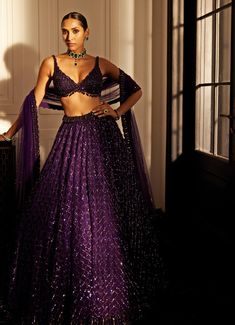 This stunning Purple Crystal and Sequin Embroidered Organza Lehenga Set exudes timeless elegance and glamour. Crafted from luxurious organza fabric, the intricately hand-embroidered purple lehenga showcases tonal detailing, shimmering sequins, and crystal embellishments that create a mesmerizing, eye-catching effect. Paired with a jewelled georgette blouse featuring intricate crystal work, this set is a perfect harmony of traditional craftsmanship and modern design. Completed with a sheer tulle dupatta, delicately adorned with matching crystal embroidery, adding a touch of ethereal charm. Ideal for making a statement at Sangeet ceremonies, weddings, or receptions. Composition : Lehenga - Organza, Dupatta - Soft Net and Blouse - Georgette Care: Dry Clean Only and Vacuum Storage This product Modern Lehenga Designs Style, Modern Lehenga Designs, Indian Reception Dress, Lehenga Purple, Modern Lehenga, Weddind Dress, Vani Vats, Bride Reception Dresses, Purple Lehenga