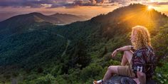 a man sitting on top of a mountain looking at the sunset