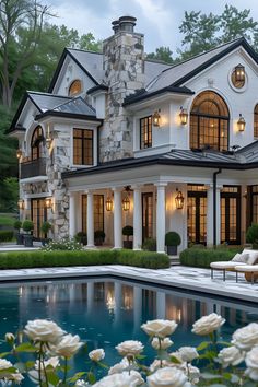 a large white house with a pool in the front yard and landscaping around it at dusk