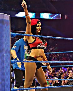 a woman standing in the middle of a wrestling ring with her arm up and fist raised