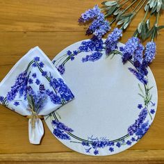 blue flowers on a white plate next to napkins and some dried lavender sprigs