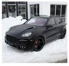 a black porsche cayen is parked in the snow