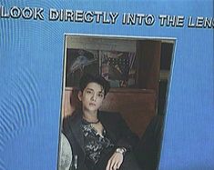 the young man is wearing a hat and sitting in front of a television screen with words on it