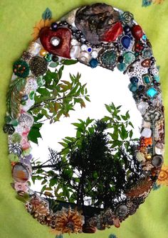 there is a tree in the middle of a circular mirror that has many different things on it