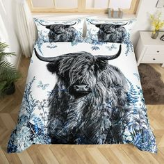 a bed with a black and white highland cow on it's side, next to a plant