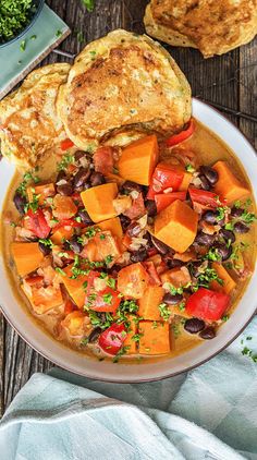 a white bowl filled with soup next to bread on top of a wooden table,