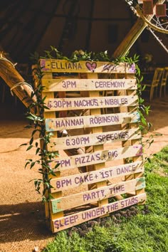 a wooden sign sitting on top of a lush green field next to a basketball hoop