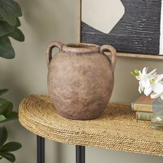 a brown vase sitting on top of a table next to a potted plant and books