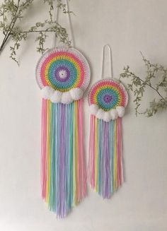 two colorful tassels hanging from hooks on a wall with flowers in the background