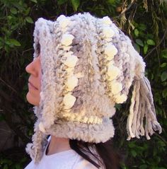 a woman wearing a knitted hat with pom poms on it's head