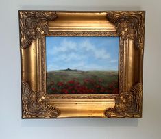 an oil painting of a field with red flowers in gold frame on the white wall