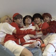 group of young men laying on top of each other in a bed with their arms around each other