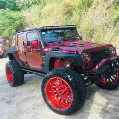 a red jeep parked on top of a dirt road