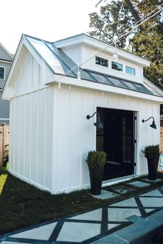 a small white shed sitting on top of a lush green field