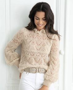 a woman in white jeans and a sweater is posing for the camera with her hands on her hips