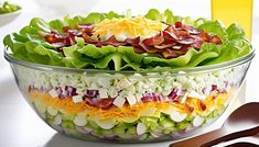 a salad with lettuce, bacon and cheese in a glass bowl