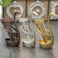 three metal swan sculptures sitting on top of a wooden floor