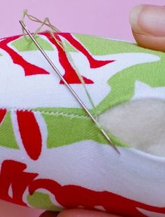 someone is stitching something on the fabric with a pair of scissors and needles in their hand