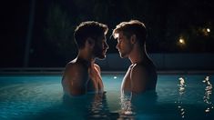 two men are in the middle of a swimming pool at night, facing each other