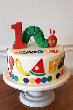 a birthday cake with the number one on it, decorated like a caterpillar and watermelon