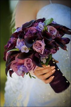 a bride holding a bouquet of purple flowers