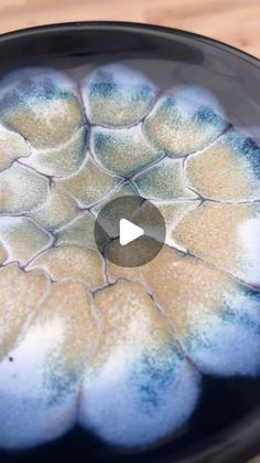 a black plate with blue and white designs on it's rim, sitting on a wooden table