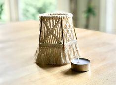 a white candle sitting on top of a wooden table next to a small container with a lid