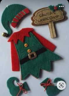 felt christmas tree decoration with santa's workshop sign and elf hat on white background