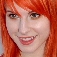 a woman with bright orange hair smiling at the camera