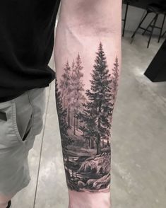 a man's arm with a black and white forest scene on the left forearm