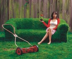 a woman sitting on top of a lawn mower next to a grass planter