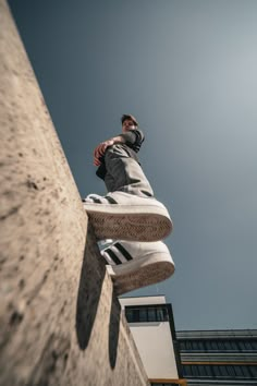 a man riding a skateboard up the side of a cement wall next to a tall building