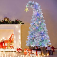 a decorated christmas tree in front of a fireplace with presents under it and lights on the mantle