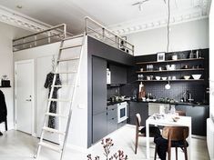 a ladder is hanging from the ceiling in a kitchen with black cabinets and white walls