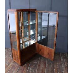 an old wooden display case with glass doors on the front and sides, sitting on a wood floor