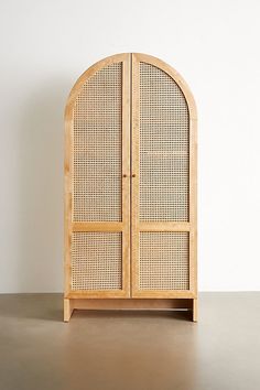 a wooden cabinet with two doors sitting on top of a table next to a white wall