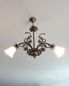 a chandelier hanging from the ceiling with three light bulbs on each side and an ornate design