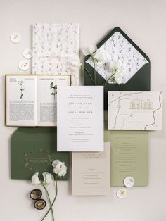 the wedding stationery is laid out on top of each other, including an open book and flowers