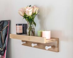 a vase with flowers and candles on a wooden shelf next to a wall mounted candle holder