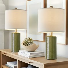 two lamps sitting on top of a wooden table next to a mirror and lamp shade