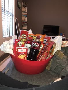 a red bowl filled with snacks and drinks on top of a table next to a tv