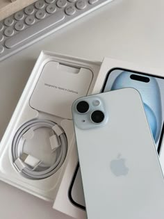 an apple iphone 11 is in its box next to the keyboard and headphones on display