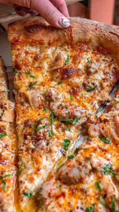 a person taking a slice of pizza from a pan with cheese and meat on it