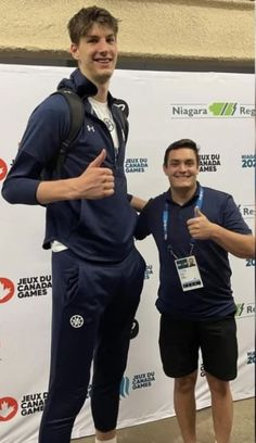 two men standing next to each other in front of a sign